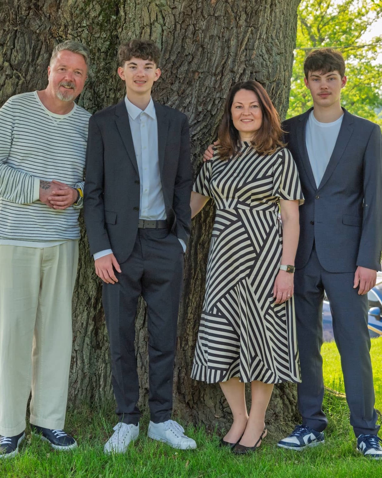 Familie in festlicher Kleidung vor einem Baum
